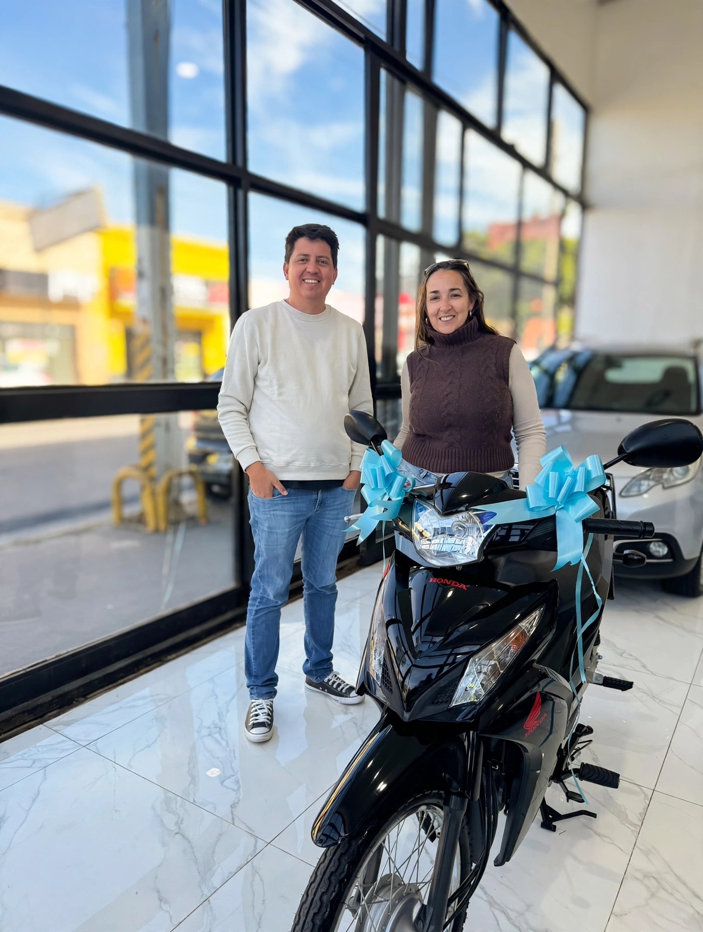 Paola Sánchez junto a Damián y la Honda Wave entregada